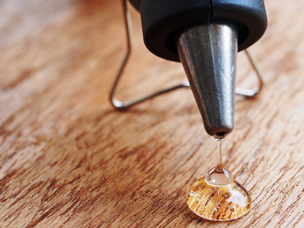 Closeup hot glue gun with melted glue dripping out